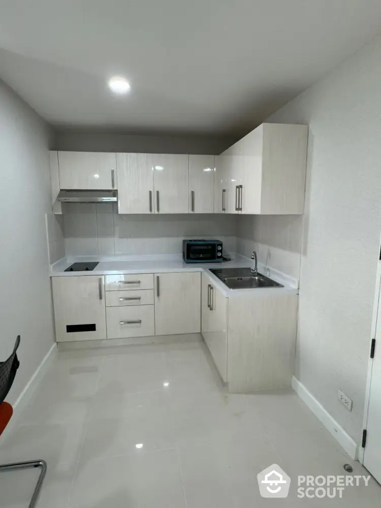 Modern compact kitchen with sleek cabinetry and built-in appliances in a bright apartment.