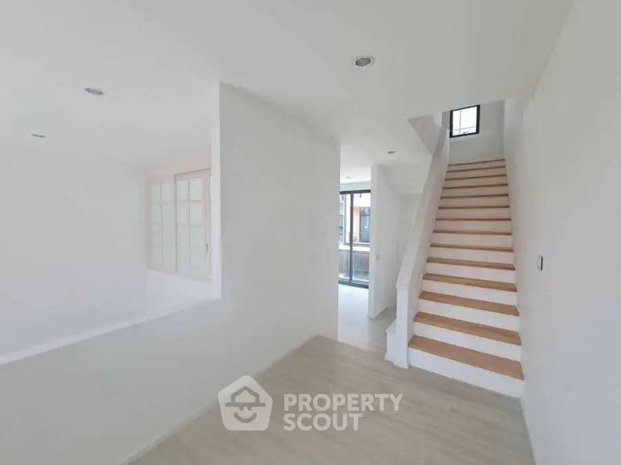 Bright modern interior with wooden staircase and large windows, perfect for natural light lovers.