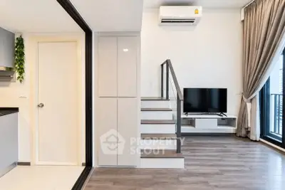 Modern living room with sleek design, featuring a TV, air conditioning, and balcony access.