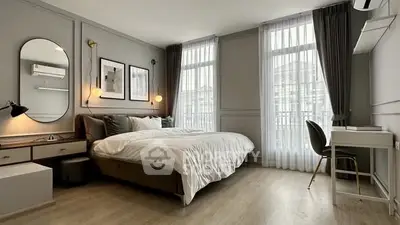 Elegant bedroom with modern decor, large windows, and a cozy workspace.