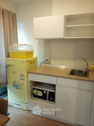 Cozy kitchen with compact fridge and modern cabinetry in a stylish apartment.