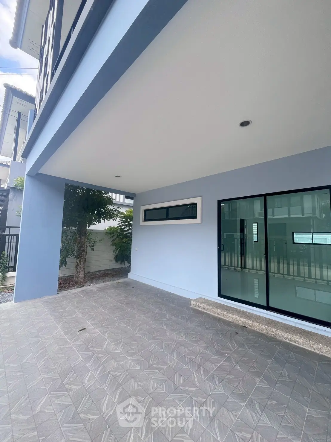 Modern residential building exterior with spacious covered patio and large glass doors.