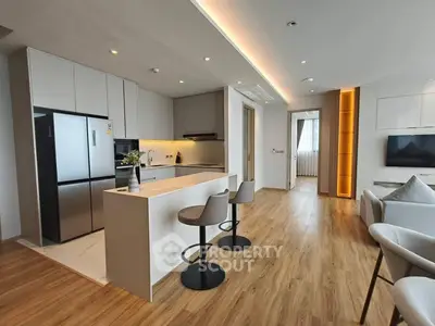 Modern open-plan kitchen and living area with sleek design and wooden flooring.