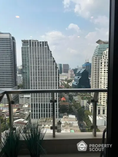 Stunning city view from modern high-rise balcony with glass railing.