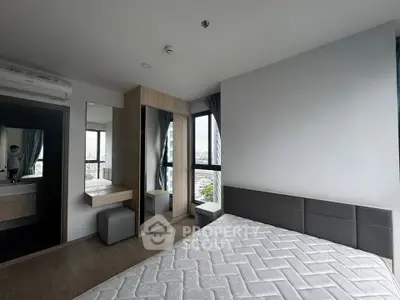 Modern bedroom with large windows and city view, featuring a stylish wardrobe and minimalist decor.