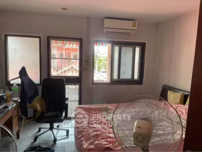 Cozy bedroom with air conditioning and natural light, featuring a comfortable bed and workspace.