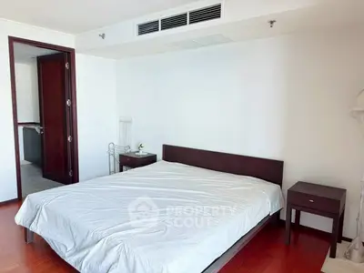 Spacious bedroom with wooden flooring and modern furnishings in a stylish apartment.