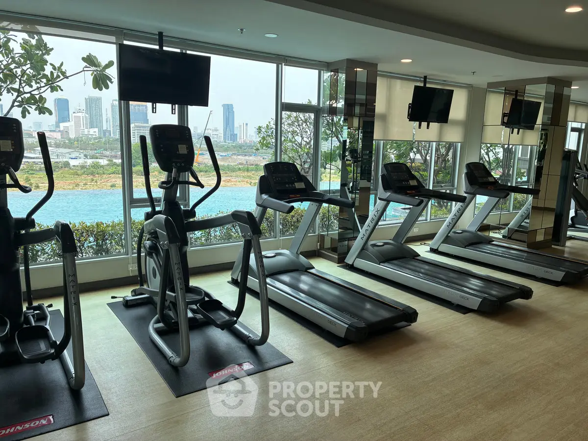 Modern gym with city view and state-of-the-art equipment in luxury residential building.