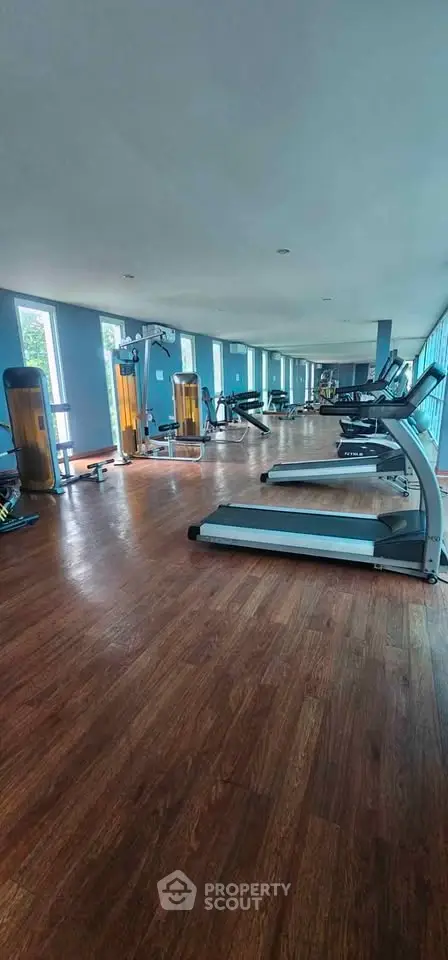 Spacious modern gym with state-of-the-art equipment and large windows for natural light.