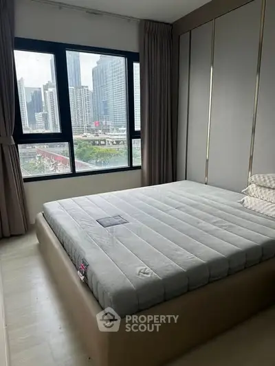 Modern bedroom with large window offering stunning city view, featuring a sleek bed and minimalist decor.