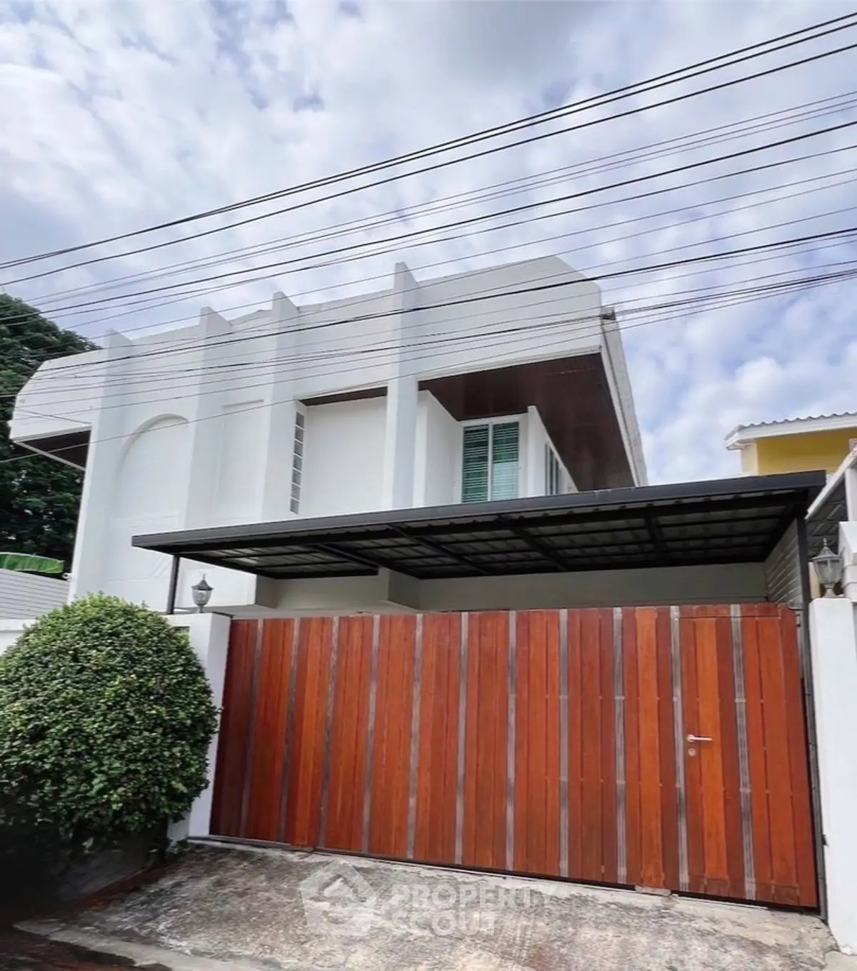 Modern two-story house with wooden gate and sleek architectural design.