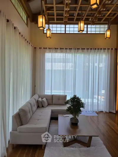 Elegant living room with modern lighting and large windows, featuring a cozy sofa and stylish coffee table.