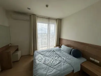 Cozy bedroom with modern furnishings and large window offering city views.