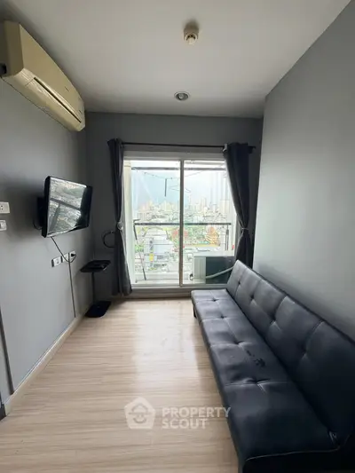 Modern living room with city view, featuring sleek black sofa and wall-mounted TV.