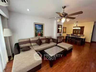 Spacious living room with elegant decor and dining area, featuring a cozy sectional sofa and ceiling fan.