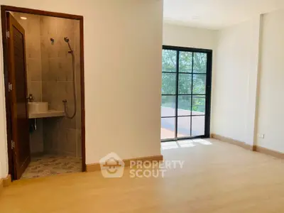 Spacious room with large window and adjacent modern bathroom, perfect for natural light lovers.