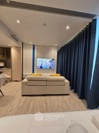 Modern living room with stylish sofa and wall-mounted TV, featuring elegant curtains and wooden flooring.