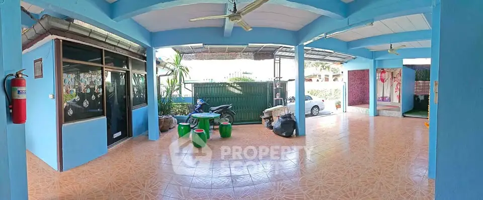 Spacious covered outdoor area with tiled flooring and ceiling fans, ideal for relaxation or parking.