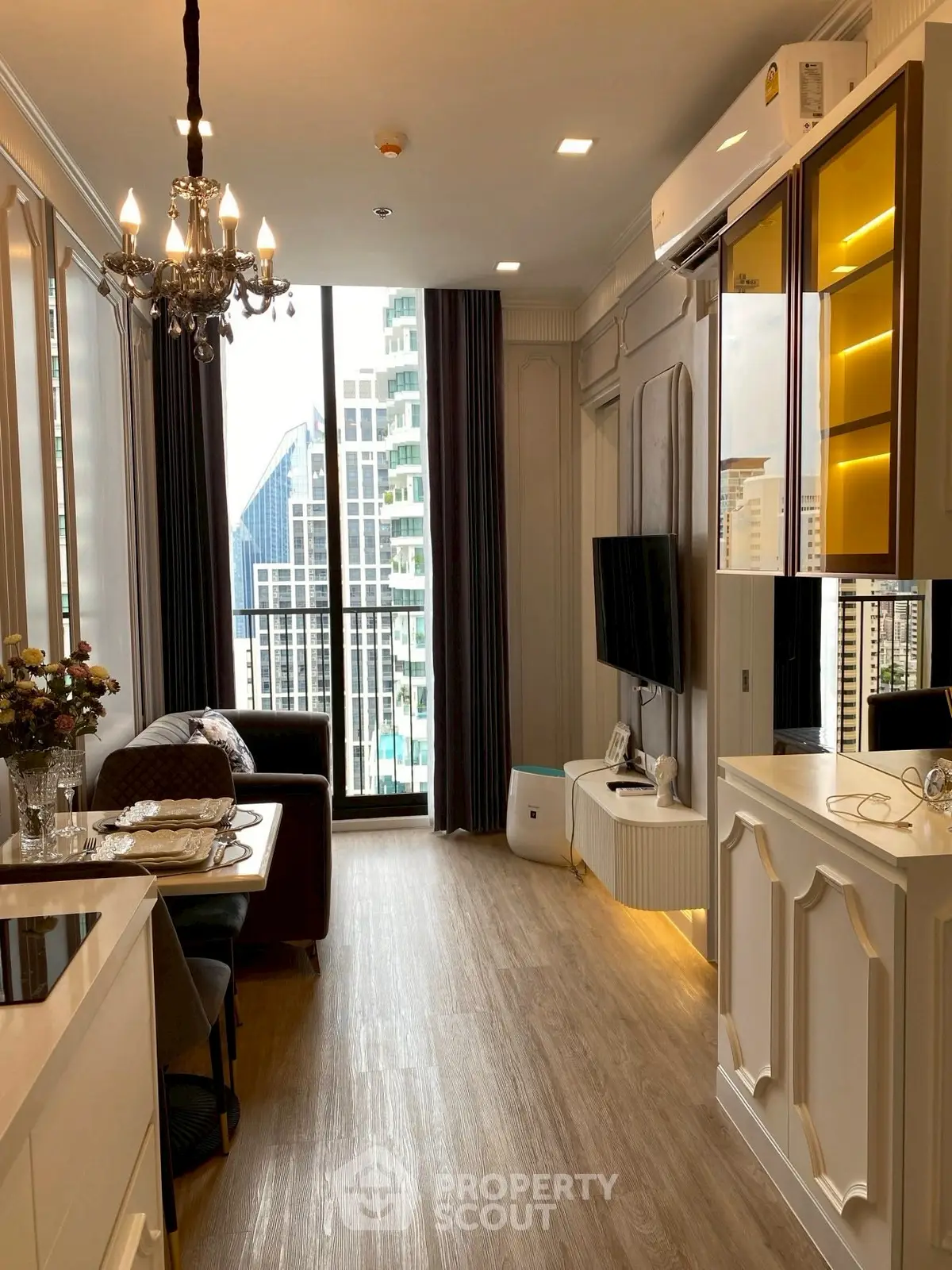 Luxurious living room with elegant chandelier and city view balcony.