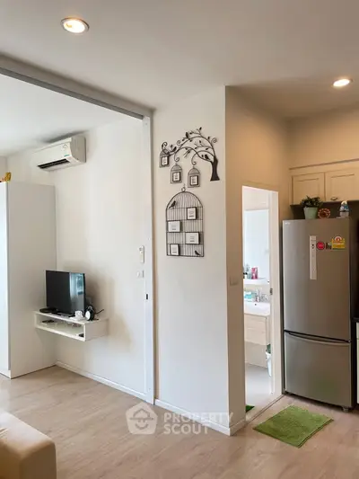 Modern living area with TV, air conditioning, and kitchen view