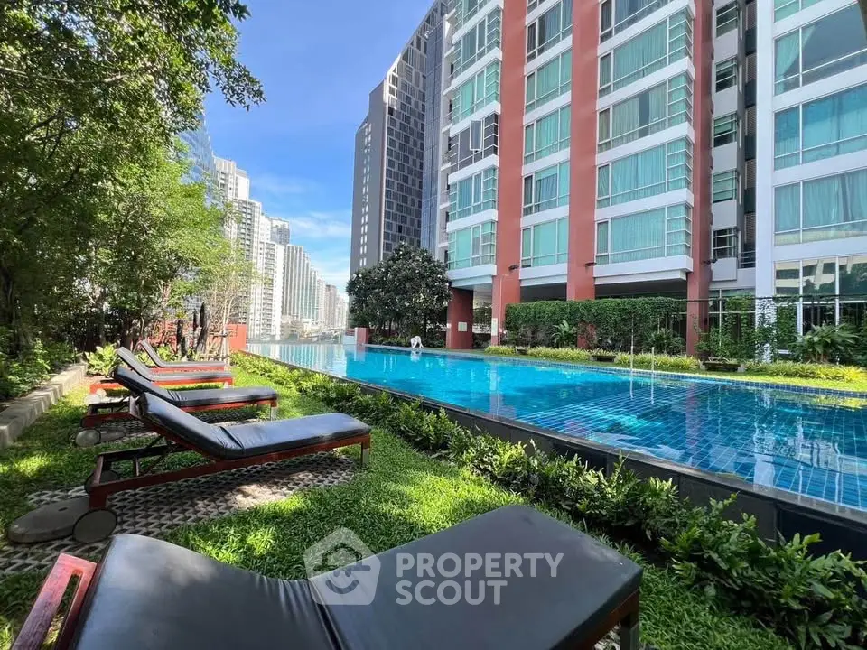 Luxurious condominium with poolside view and lush greenery in urban setting.