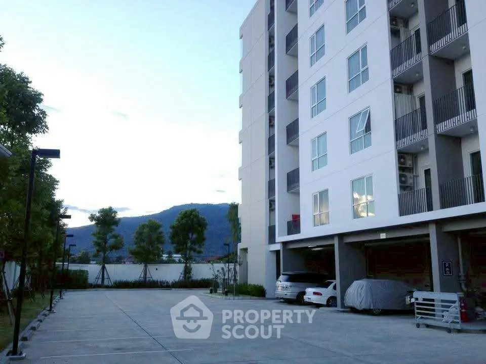 Modern apartment building with spacious parking area and scenic mountain view.