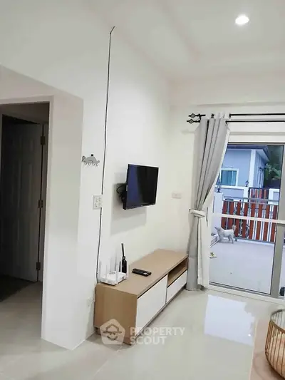 Modern living room with wall-mounted TV and sliding glass doors leading to a balcony.