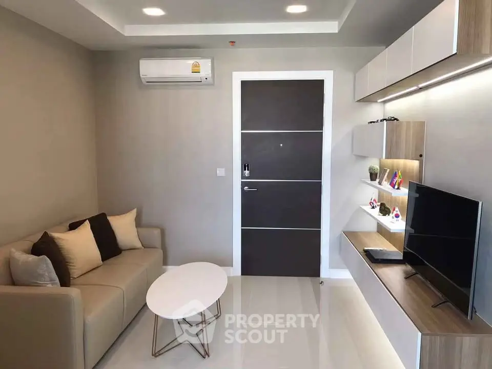 Modern living room with sleek furniture and wall-mounted TV in a stylish apartment.