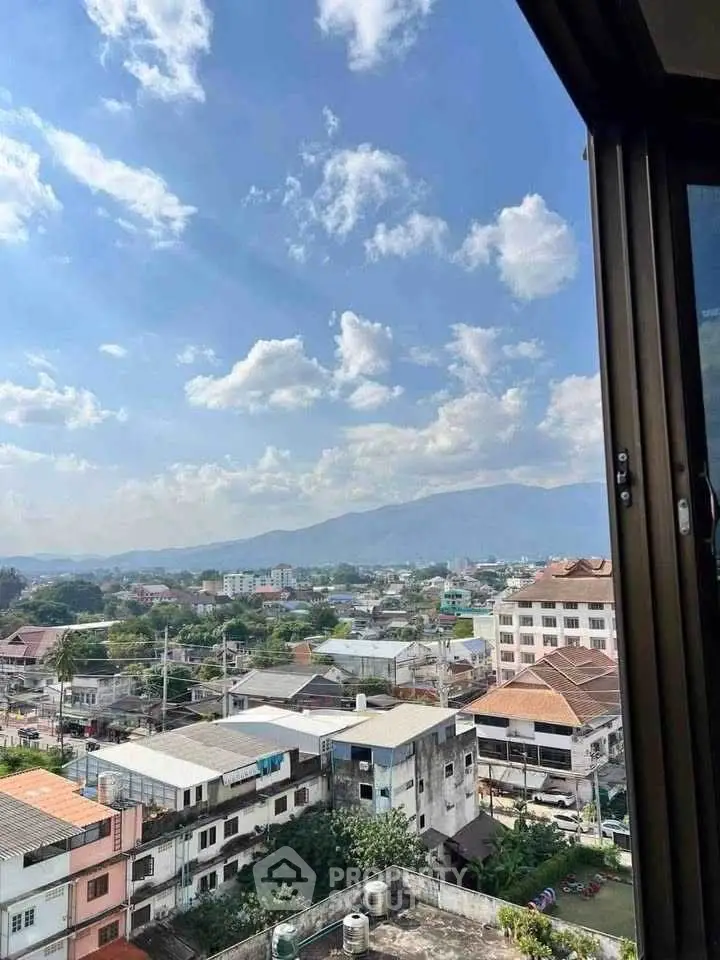 Stunning cityscape view from a high-rise window showcasing urban living with mountain backdrop.