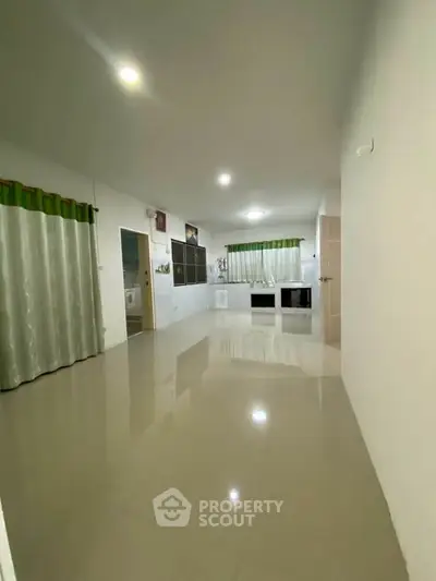 Spacious open-plan living area with glossy tiled floors and modern lighting.