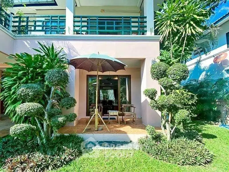 Charming garden view of a modern home with lush greenery and cozy patio seating.