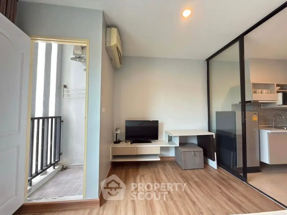 Modern living room with balcony access and sleek kitchen area in a stylish apartment.