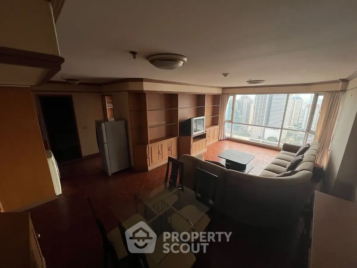 Spacious living room with city view, featuring modern furniture and large windows for natural light.