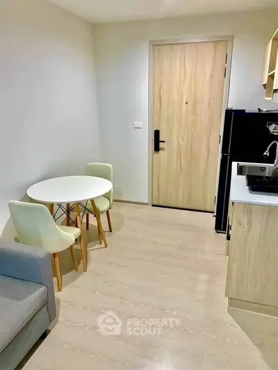 Modern compact living room with dining area and kitchenette in cozy apartment.