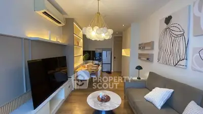 Modern living room with stylish decor and open dining area, featuring contemporary lighting and wall art.