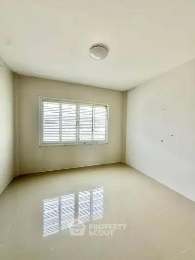 Spacious empty room with large window and glossy tiled floor, perfect for customization.