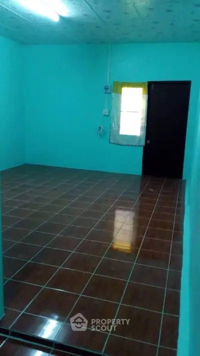 Spacious room with tiled flooring and bright teal walls, ideal for versatile use.