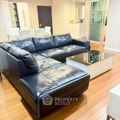 Spacious living room with black leather sectional and modern decor