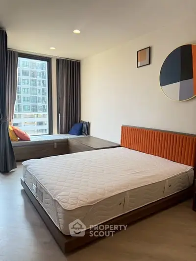 Modern bedroom with stylish decor and large window offering city view