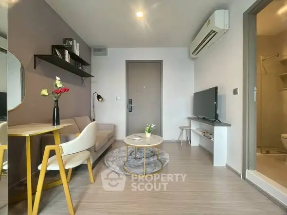 Modern living room with cozy seating, stylish decor, and air conditioning in a compact apartment.