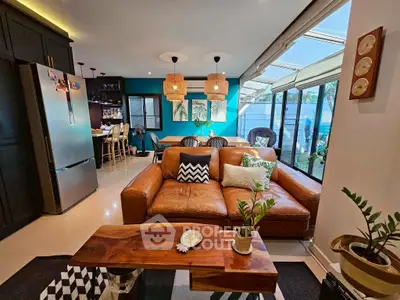 Stylish open-plan living room with leather sofa, modern kitchen, and large windows for natural light.