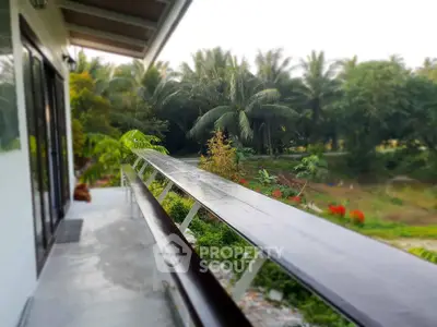 Charming balcony with lush garden view in serene tropical setting.