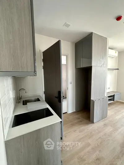 Modern compact kitchen with sleek cabinetry and integrated appliances in a stylish apartment.