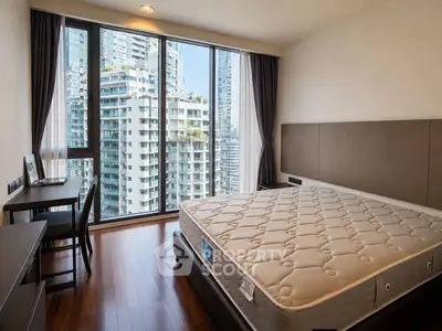 Spacious bedroom with large windows offering stunning city views in a modern high-rise apartment.