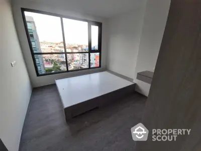 Modern bedroom with large window and city view, featuring sleek flooring and minimalist design.