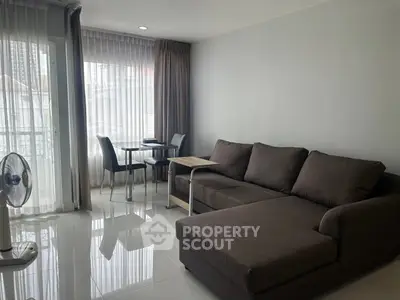 Modern living room with large sofa and dining area, featuring natural light and sleek design.