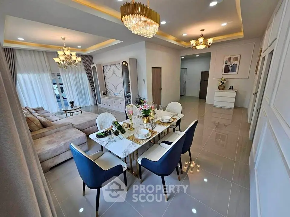 Luxurious open-plan living and dining area with elegant chandeliers and modern decor.