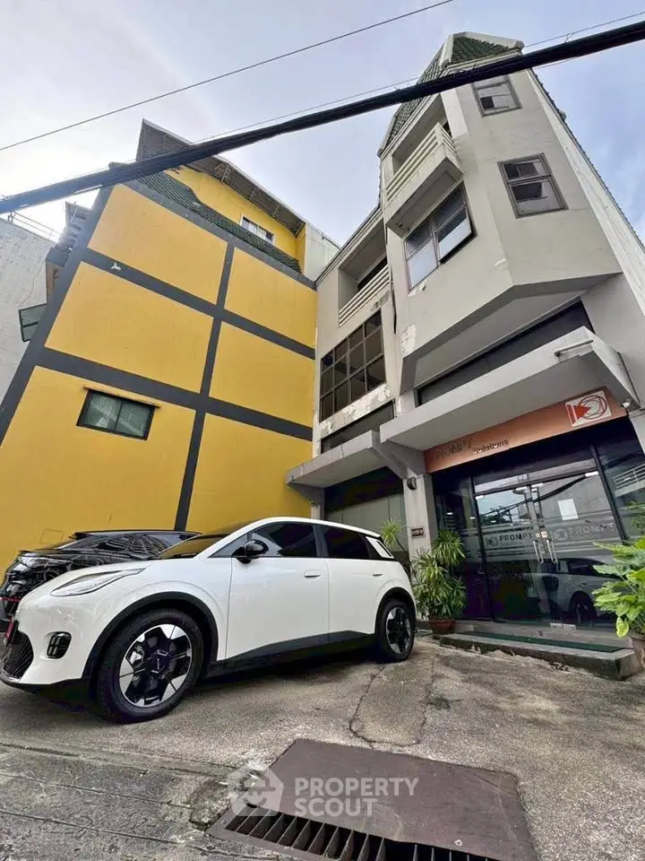 Modern urban building with parking area and stylish car in front