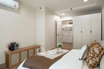 Cozy bedroom with modern decor and view into a sleek kitchen, perfect for urban living.