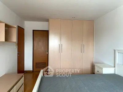 Spacious bedroom with modern wardrobe and wooden flooring in a stylish apartment.